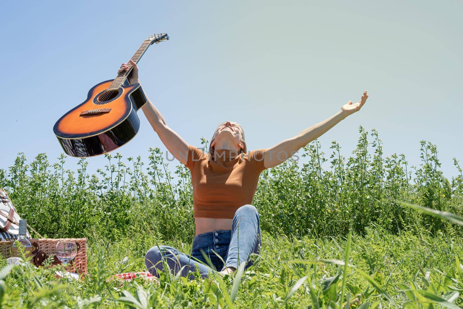 Young woman playing guitar on a picnic by Desperada