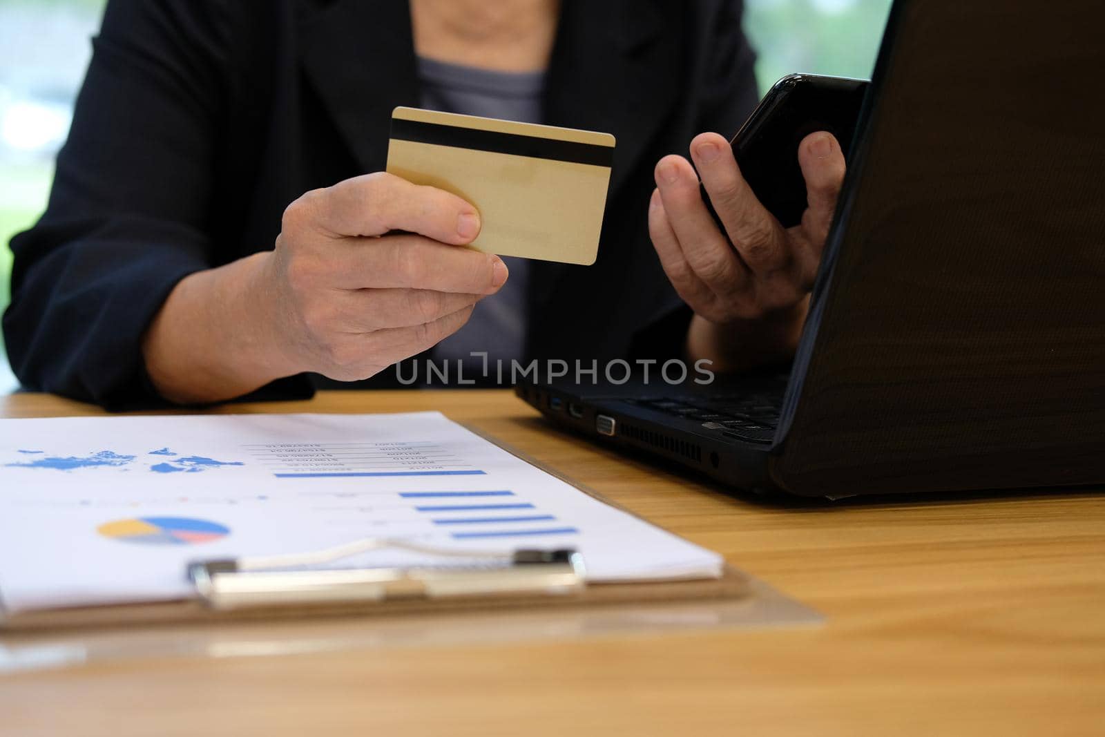 woman holding credit card using smart phone for online shopping. businesswoman purchase product from internet, make payment on bank website at workplace