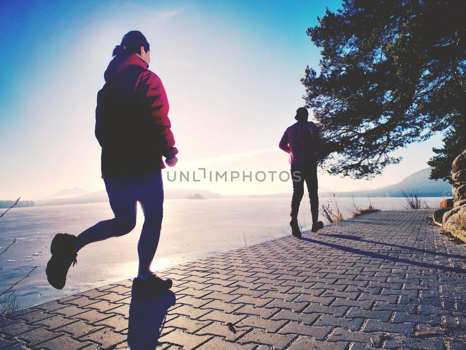 Couple jumping in the sun on a dock of lake.  Happy people do sports together, condition training. 