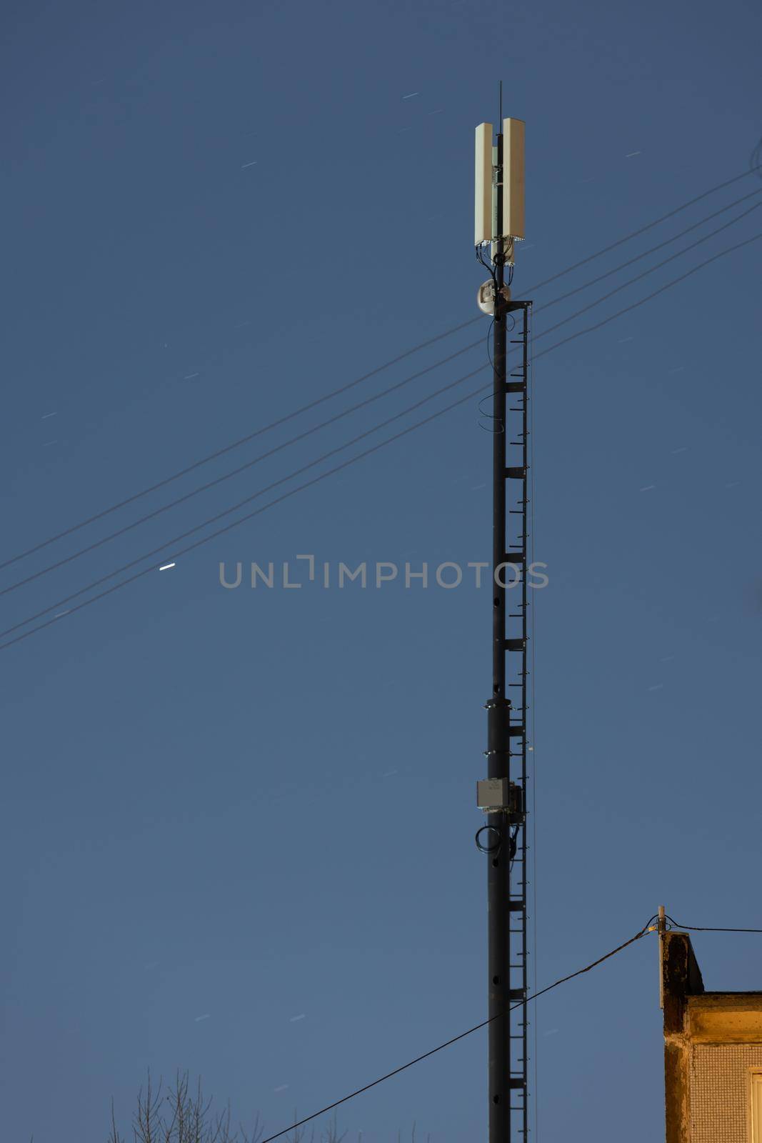 long lightweight internet telecommunication pipe tower with 4g and 5g transmitters at night.