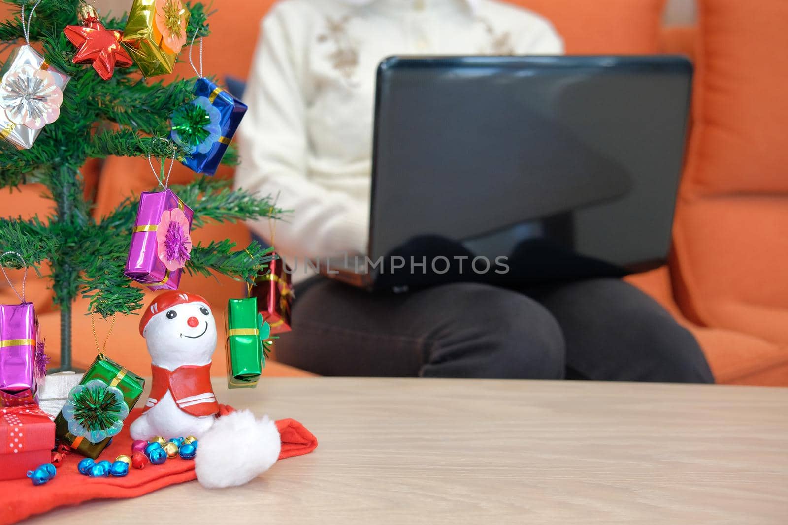 woman sitting on sofa at home using computer during xmas. christmas holiday new year celebration season greetings.