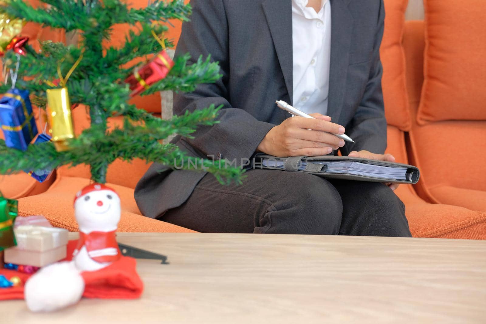 woman wearing suit holding notebook with gift present box christmas tree on table. xmas new year celebration.