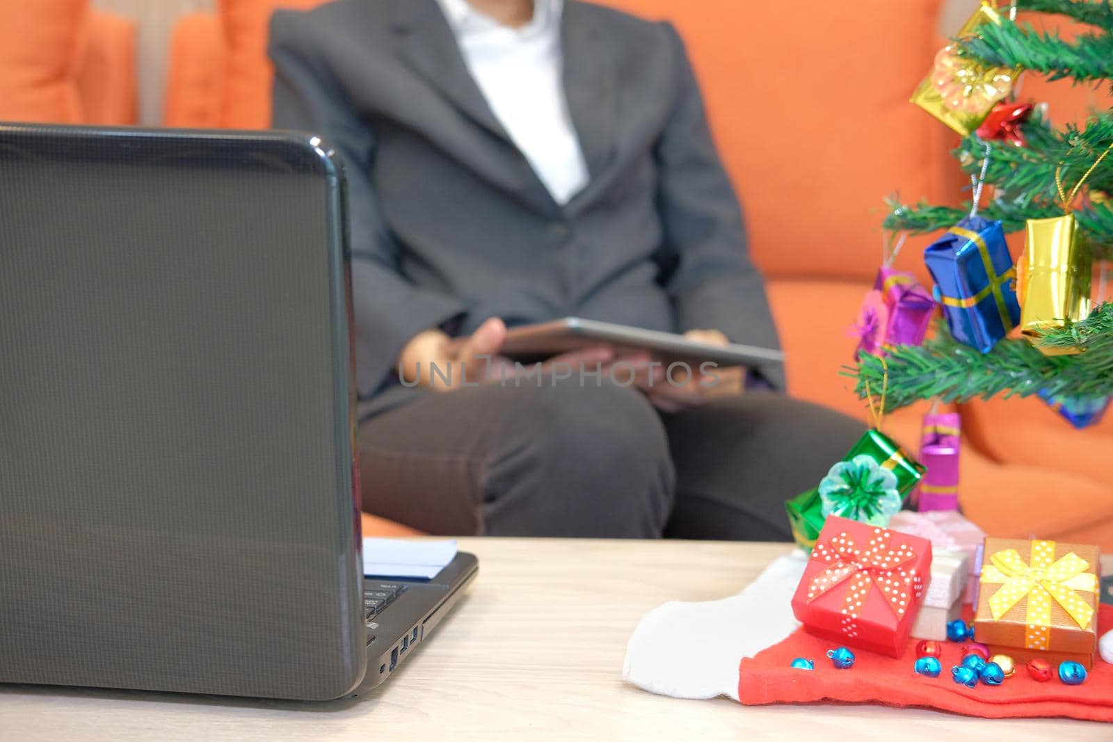 man sitting on sofa using tablet. businesswoman texting message on touchpad during xmas. christmas holiday new year celebration season greetings