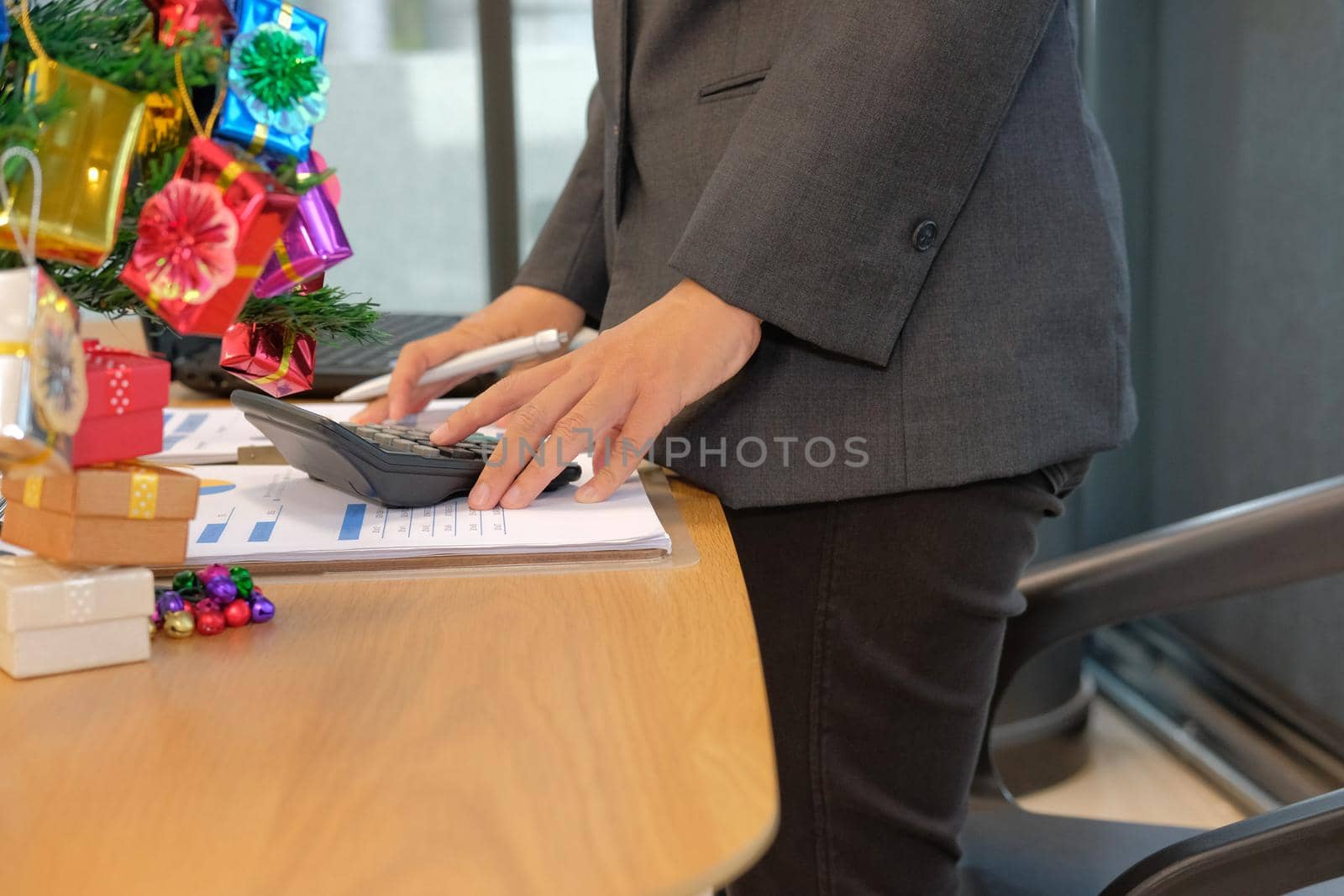 financial adviser working with calculator at office. accountant doing accounting & calculating revenue & budget. bookkeeper making calculation during christmas new year holiday