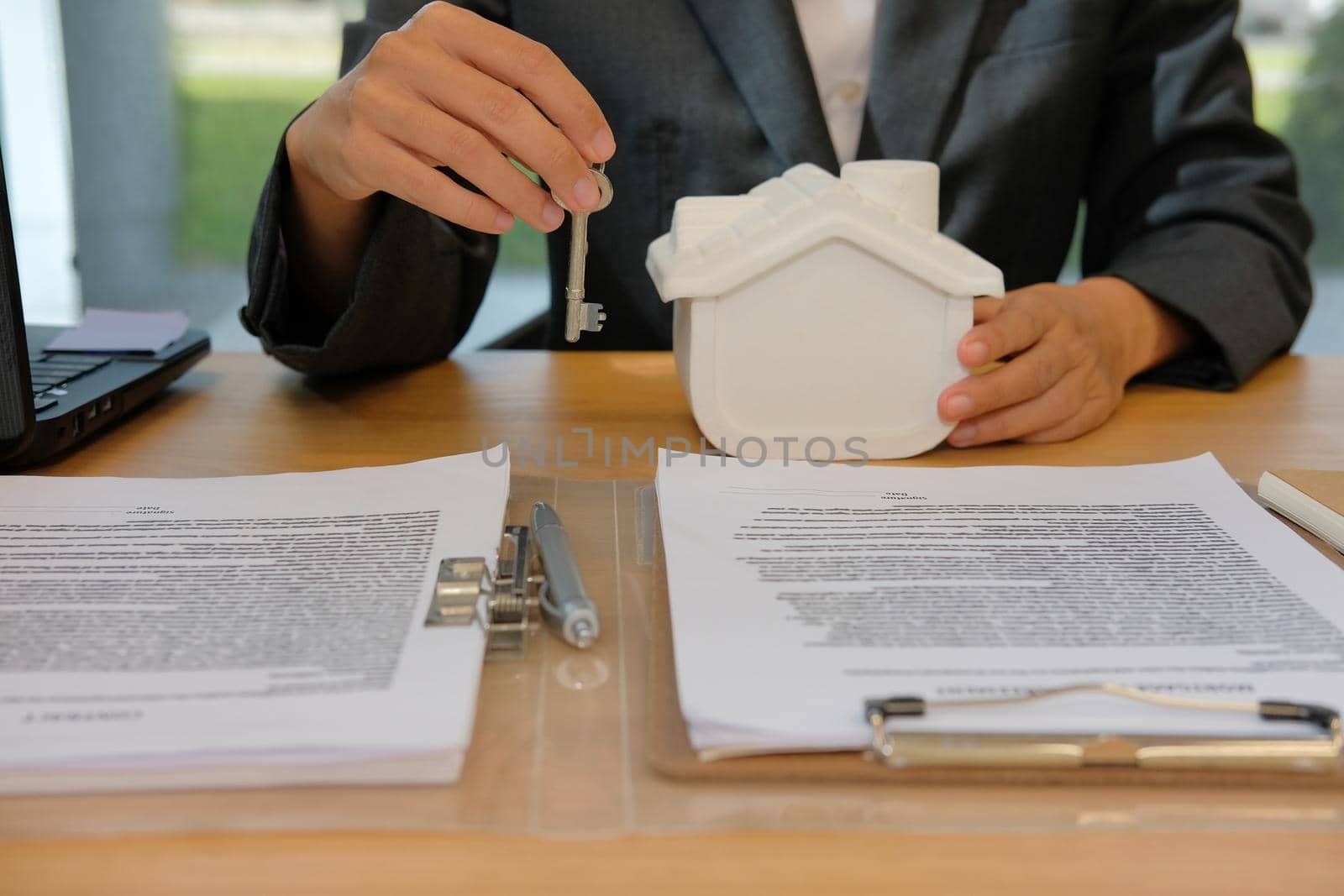 realtor agent with house model, key & mortgage loan agreement. buying renting real estate property