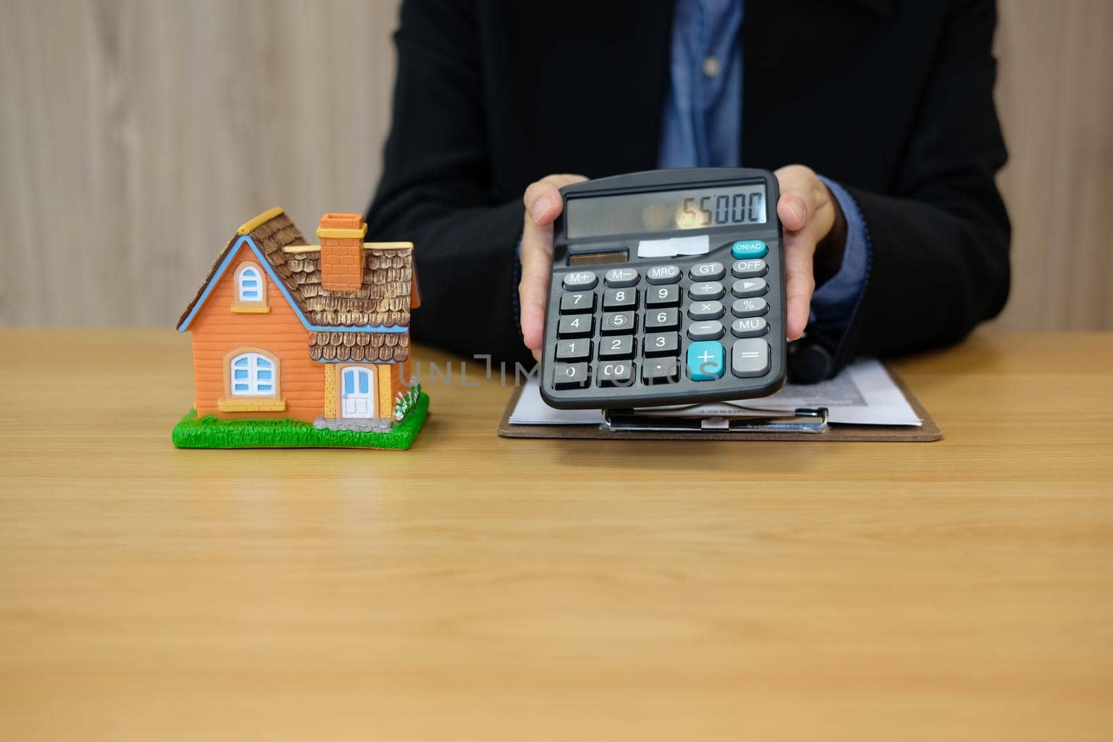 realtor agent with house model showing calculated price number on calculator. buying renting property. real estate insurance.