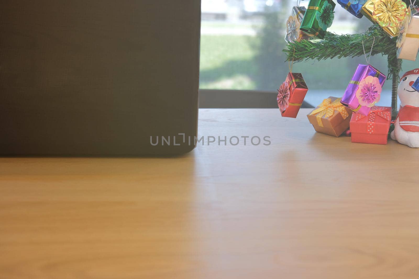 computer christmas tree decorated with gift box snowman on office desk at workplace