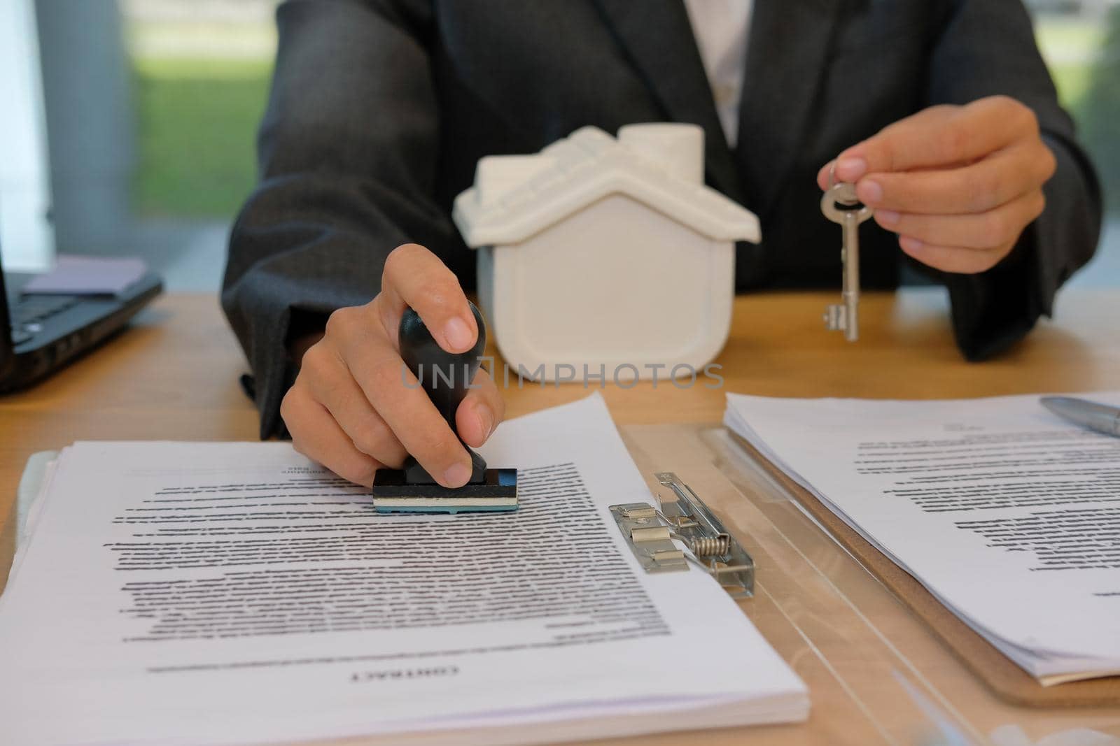 real estate agent with house key using stamper for stamping approved on mortgage loan contract agreement document