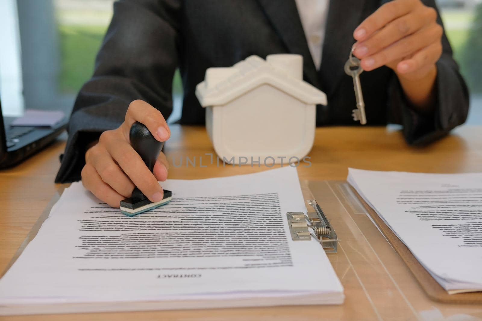 real estate agent with house key using stamper for stamping approved on mortgage loan contract agreement document