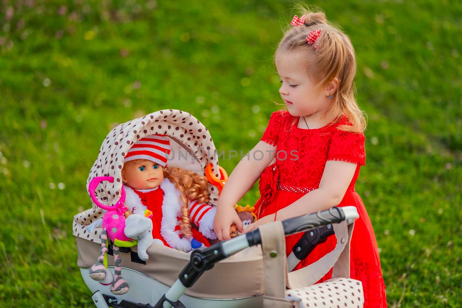 girl plays with her doll who is sitting in a toy stroller