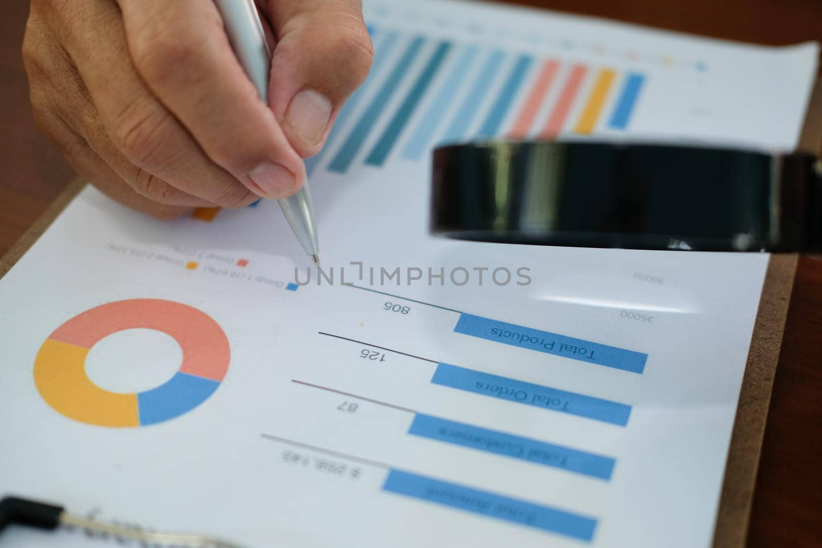 businessman checking chart & diagaram in business document with magnifying glass