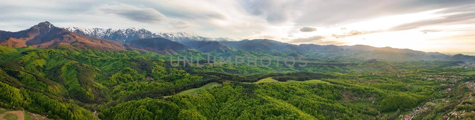 Stunning panoramic view from a drone of the mountain with snow peaks and green hills.