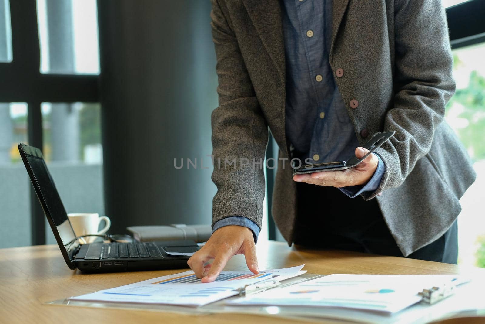 man working organizing plan with smart phone. businessman analyzing document at workplace coworking office