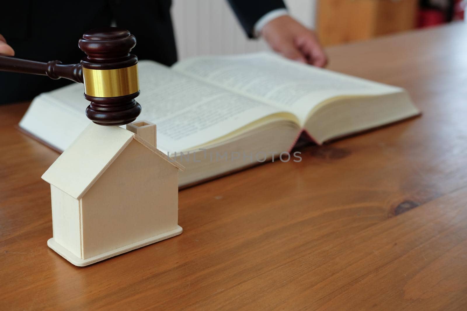 lawyer with judge gavel knocking house model with law book at courtroom. real estate dispute & property auction concept
