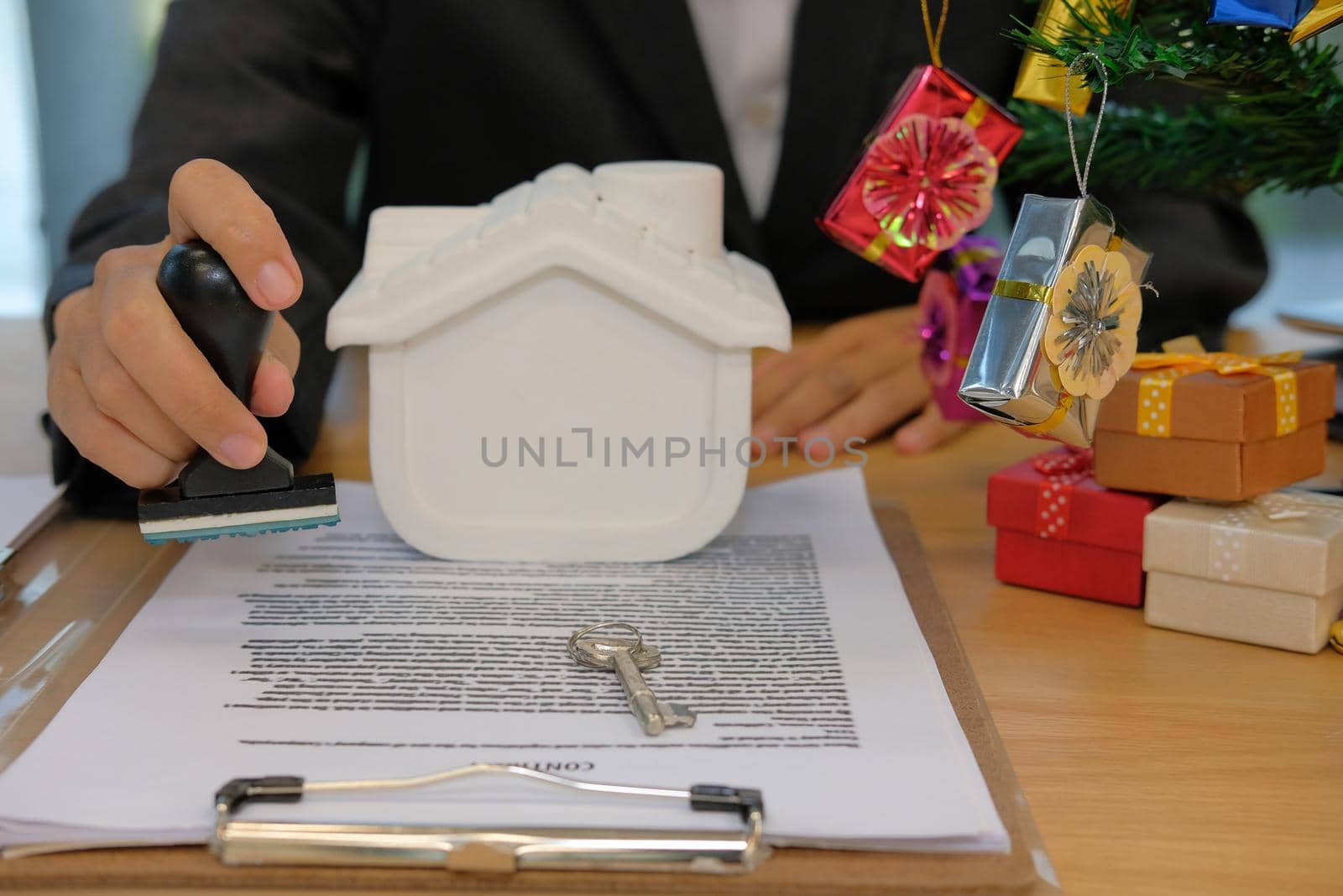 real estate agent with house key using stamper for stamping approved on mortgage loan contract agreement document during christmas
