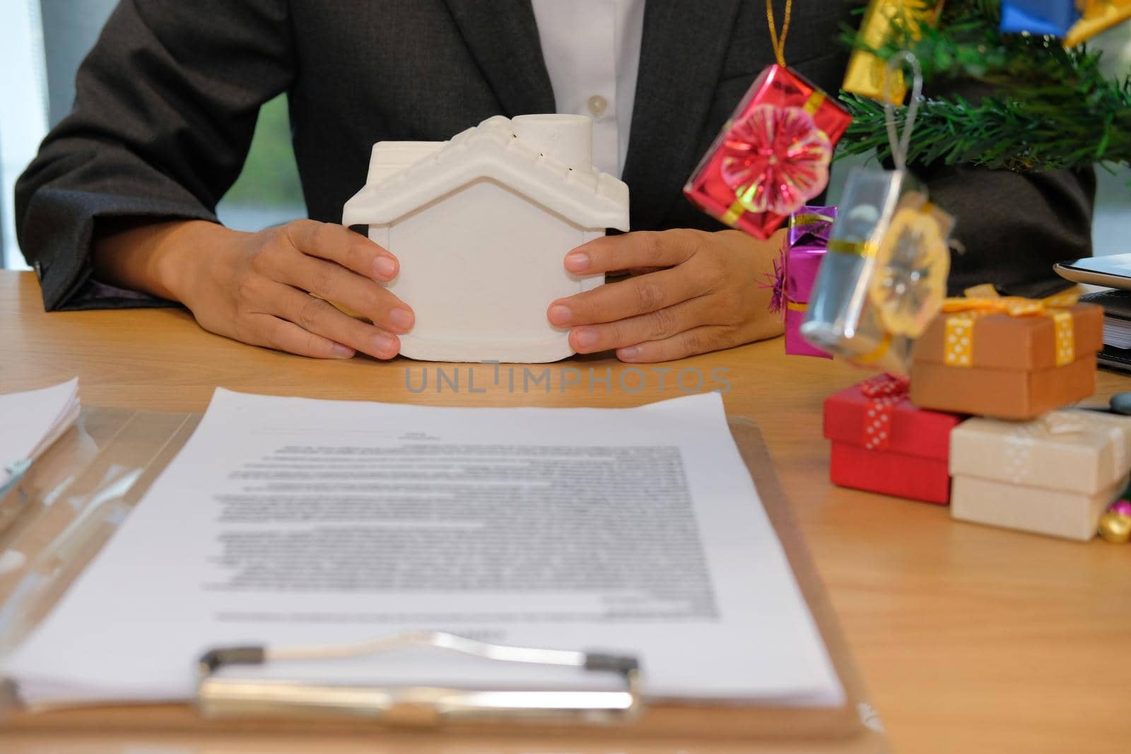 hand holding house model with real estate insurance contract. property ownership at christmas by pp99