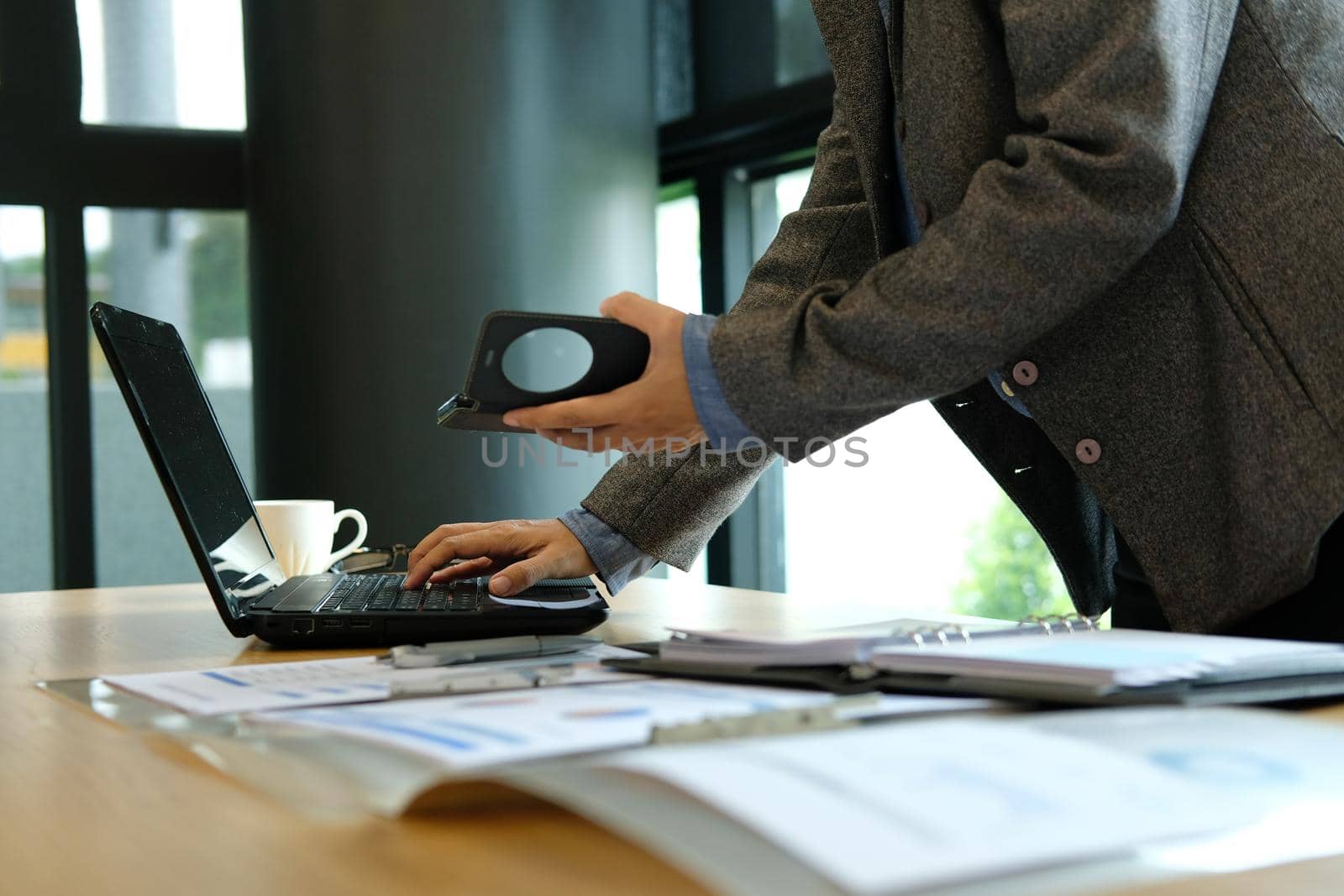 man organizing plan with smart phone. businessman working with computer at workplace by pp99