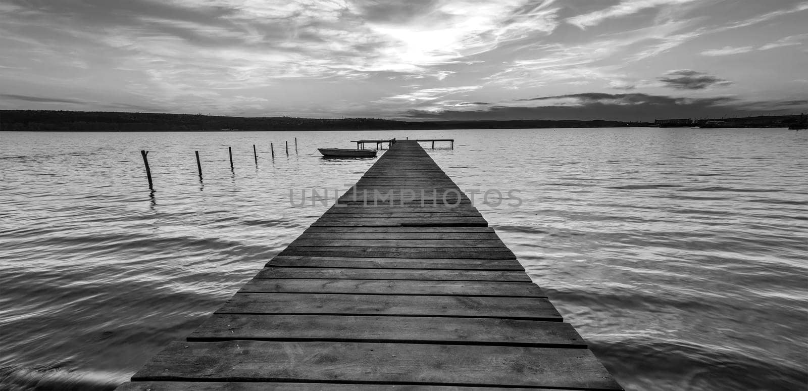 Exciting twilight at the shore with wooden pier and moored boat