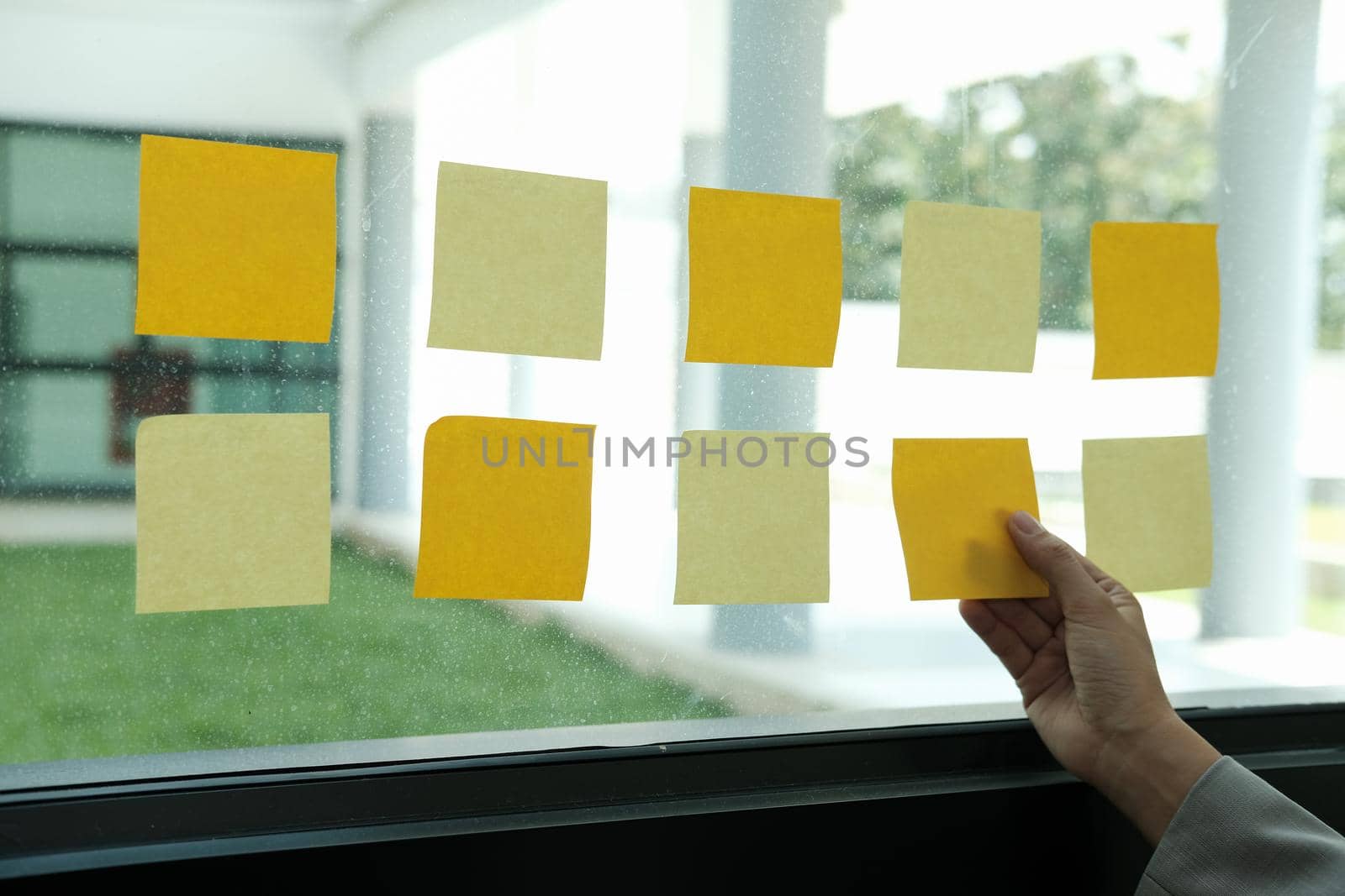 hand hold adhesive notes on glass wall. Sticky note paper reminder schedule for creative idea & business brainstorming by pp99