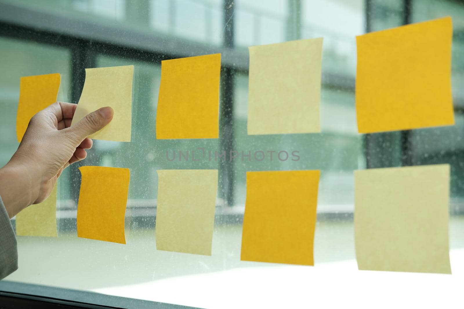 hand hold adhesive notes on glass wall. Sticky note paper reminder schedule for creative idea & business brainstorming by pp99