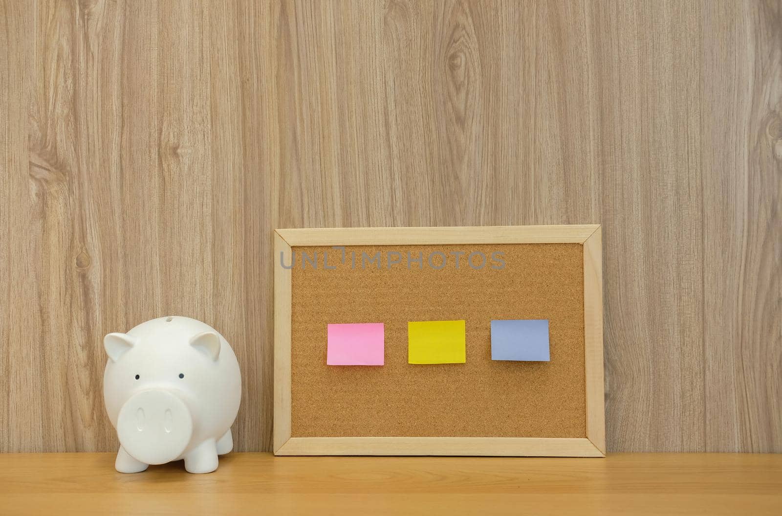 sticky notes paper reminder on cork board & piggy bank on wooden desk. money saving finance investment concept