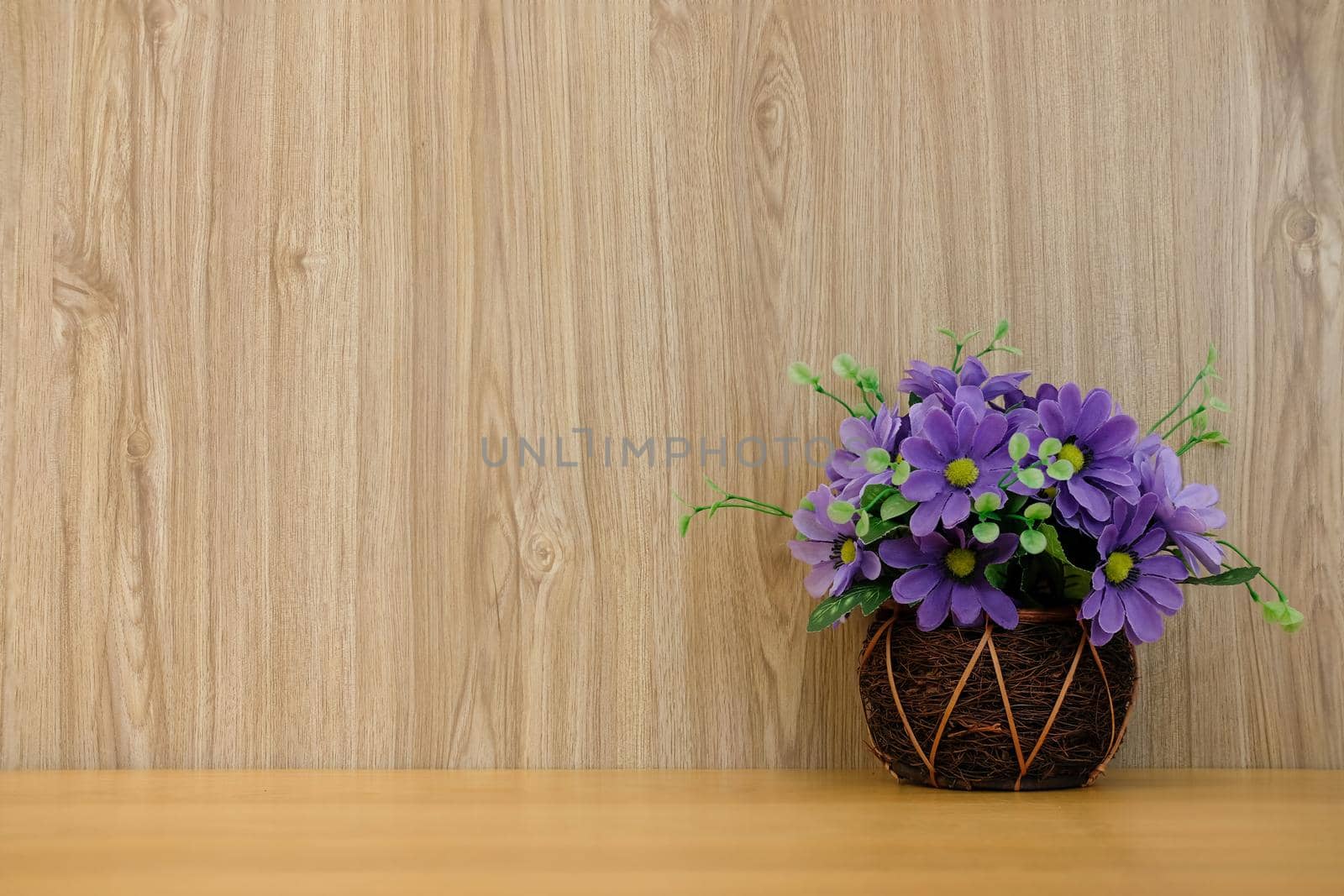 purple artificial flower on wooden table at office workplace