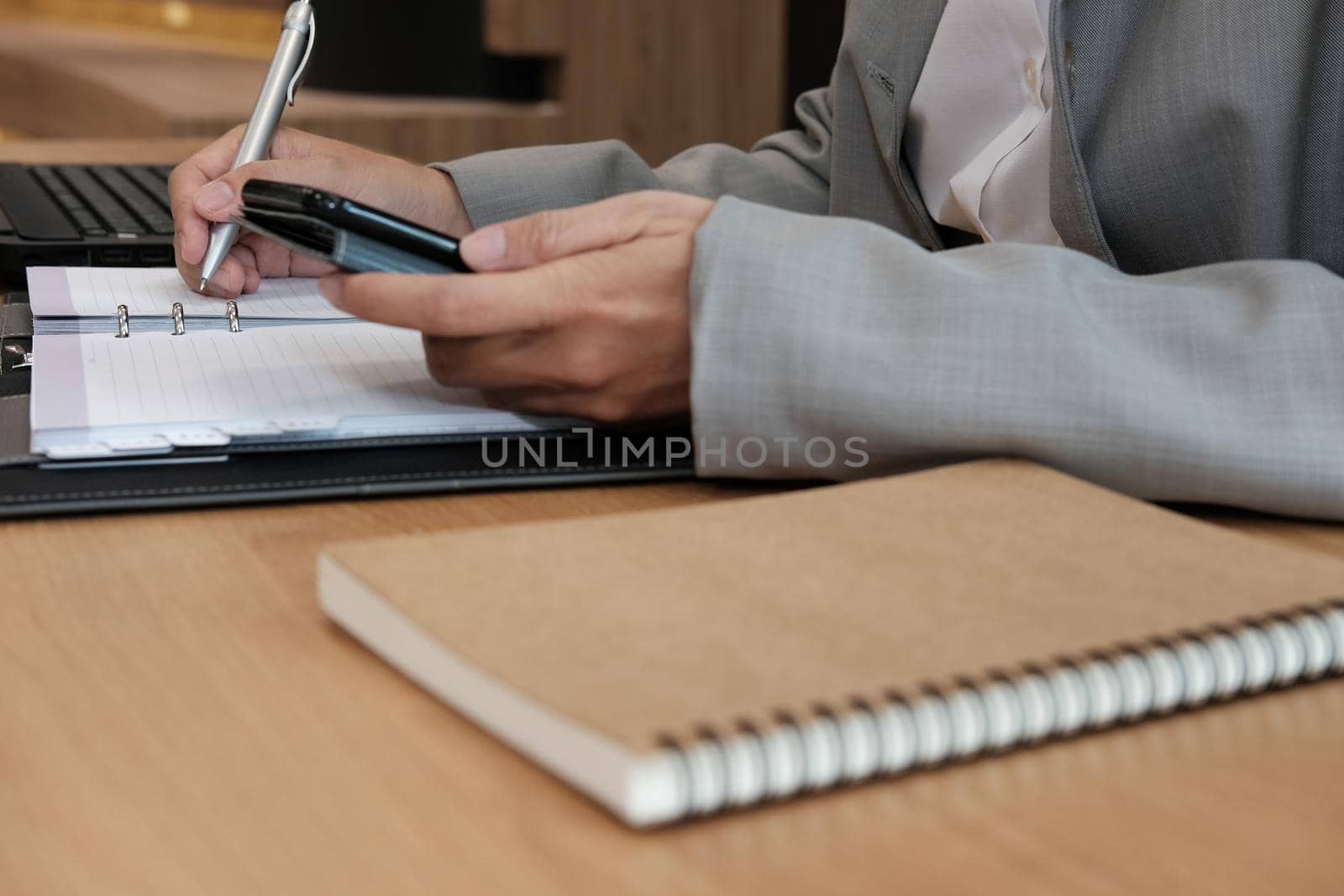 man writing reminder schedule note on notebook. businessman working organizing plan with smart phone at workplace coworking office