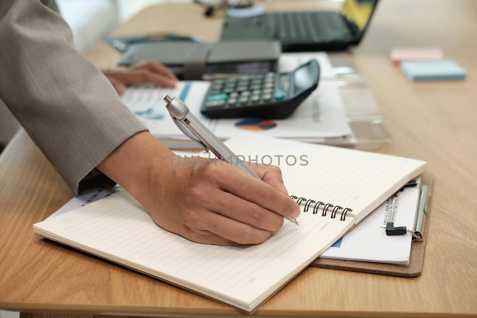 man writing reminder schedule note on notebook. businessman working organizing plan at workplace coworking office