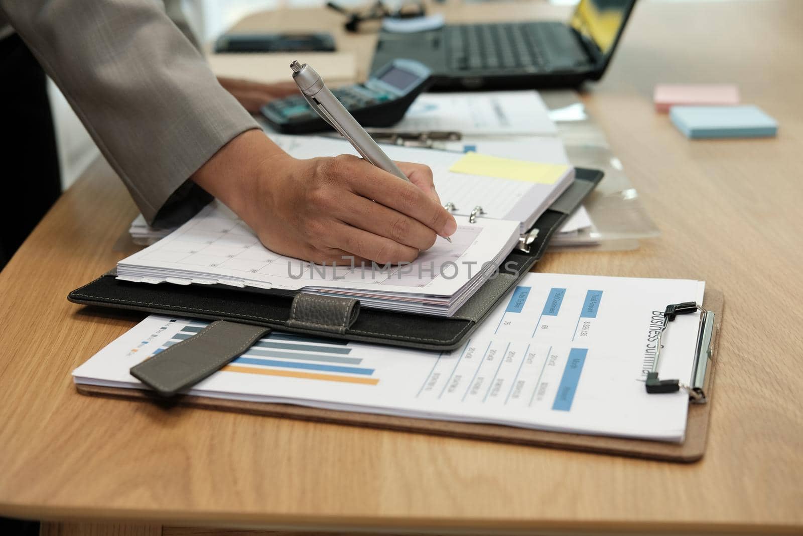 man writing reminder schedule note on notebook. businessman working organizing plan at workplace coworking office