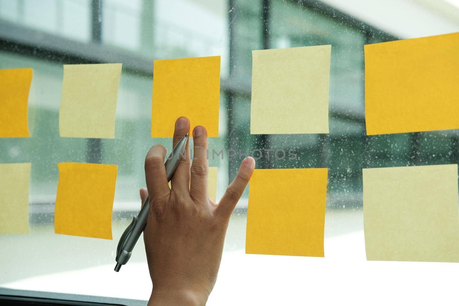 hand touch on adhesive notes on glass wall. Sticky note paper reminder schedule for creative idea & business brainstorming by pp99
