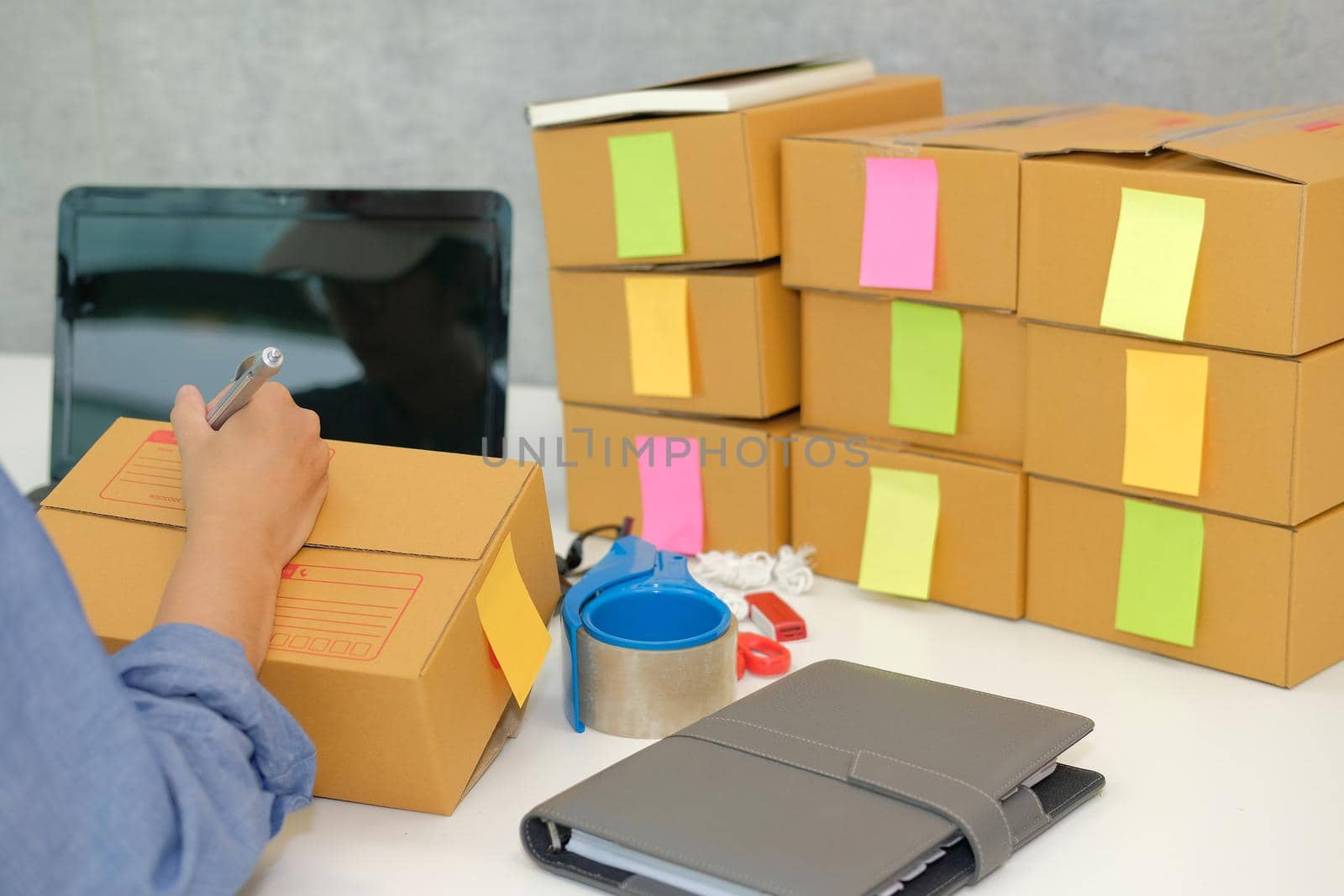 startup small business owner writing address on cardboard box at workplace. freelance woman entrepreneur seller prepare parcel box for delivery product to customer.  Online selling, e-commerce concept
