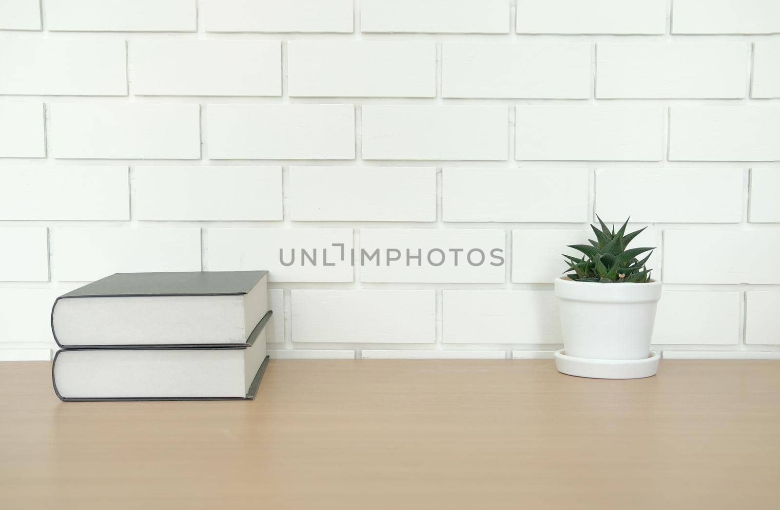 book on wooden desk near white brick wall. office workplace top view by pp99