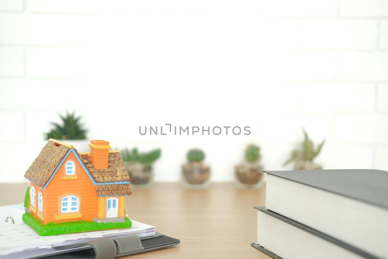 book & house model on wooden desk. realtor real estate agent workplace. buying selling & renting property