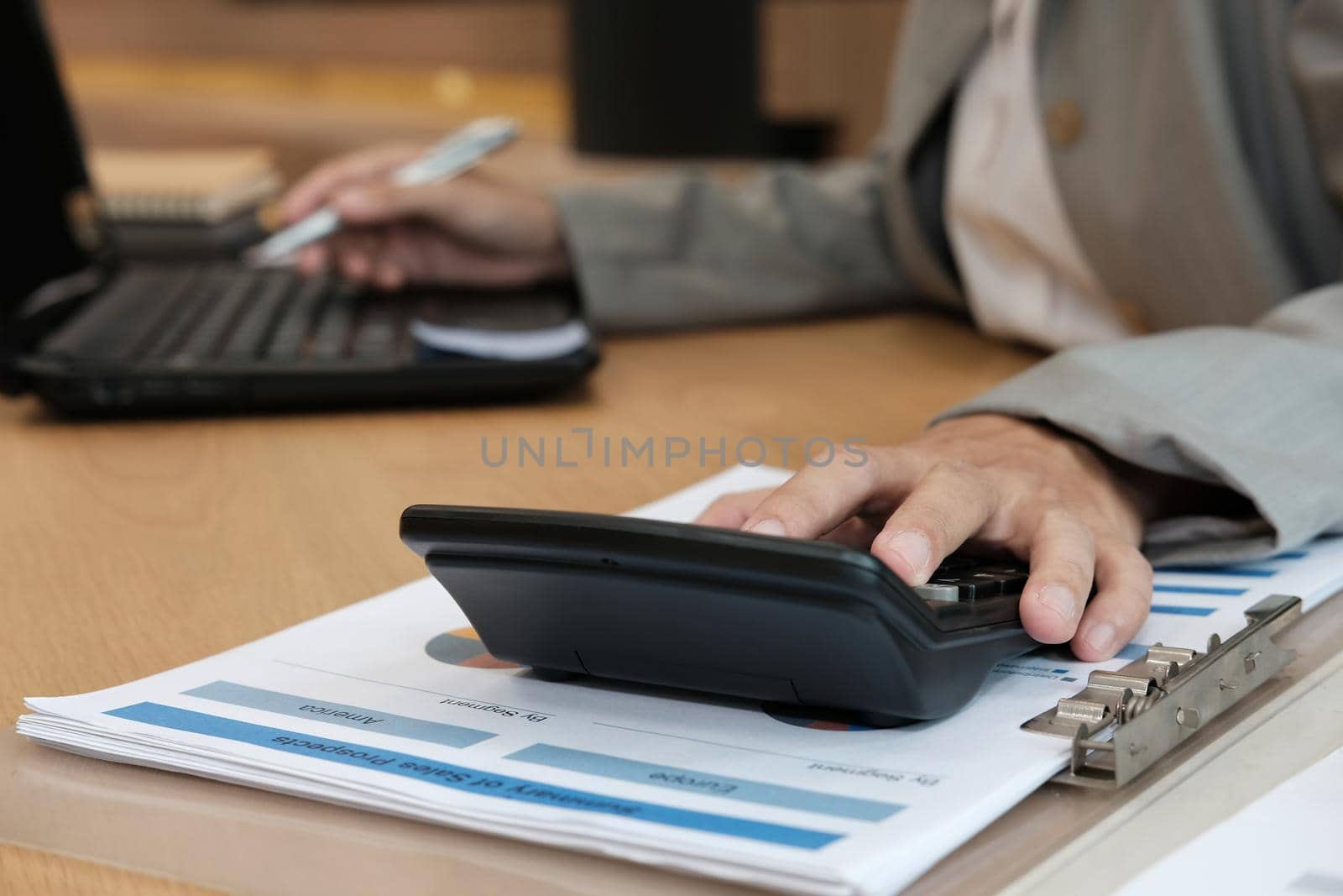 financial adviser working with calculator & computer at office. accountant doing accounting & calculating revenue & budget. bookkeeper making calculation. finance & economy concept