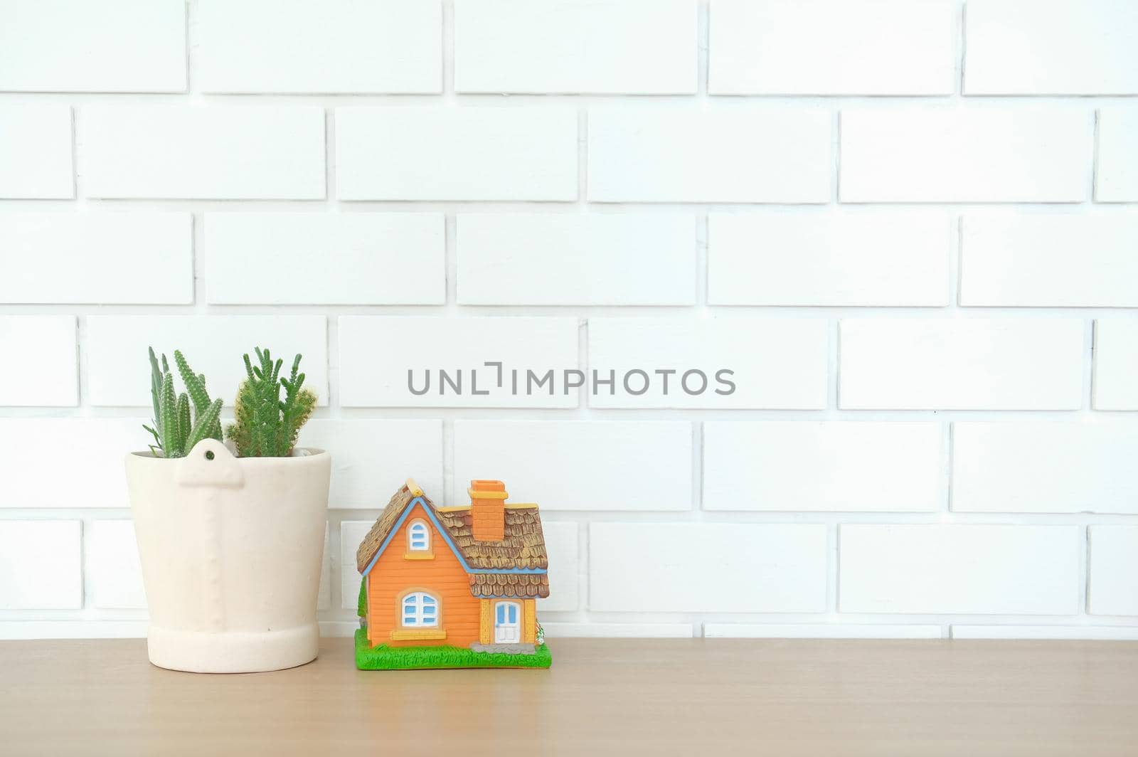 house model on wooden desk near white brick wall. realtor real estate agent workplace. buying selling & renting property