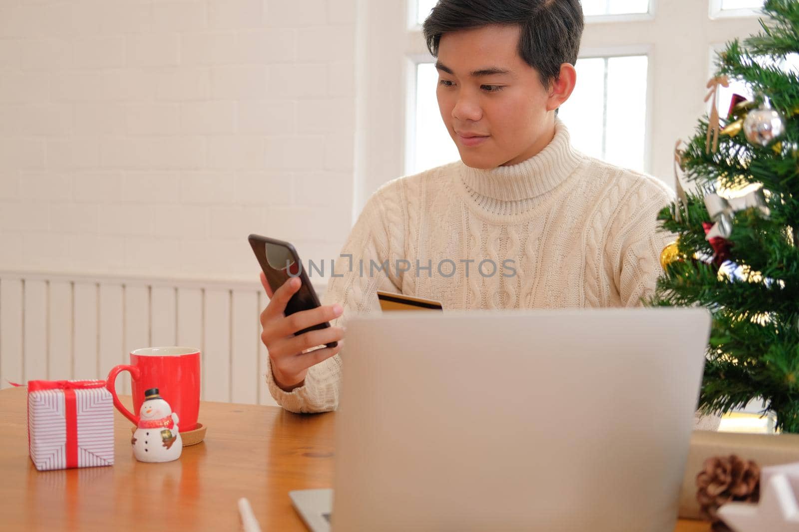 man holding credit card & smart phone for online shopping.  male buyer buying christmas gift on internet. merry xmas new year holiday celebration