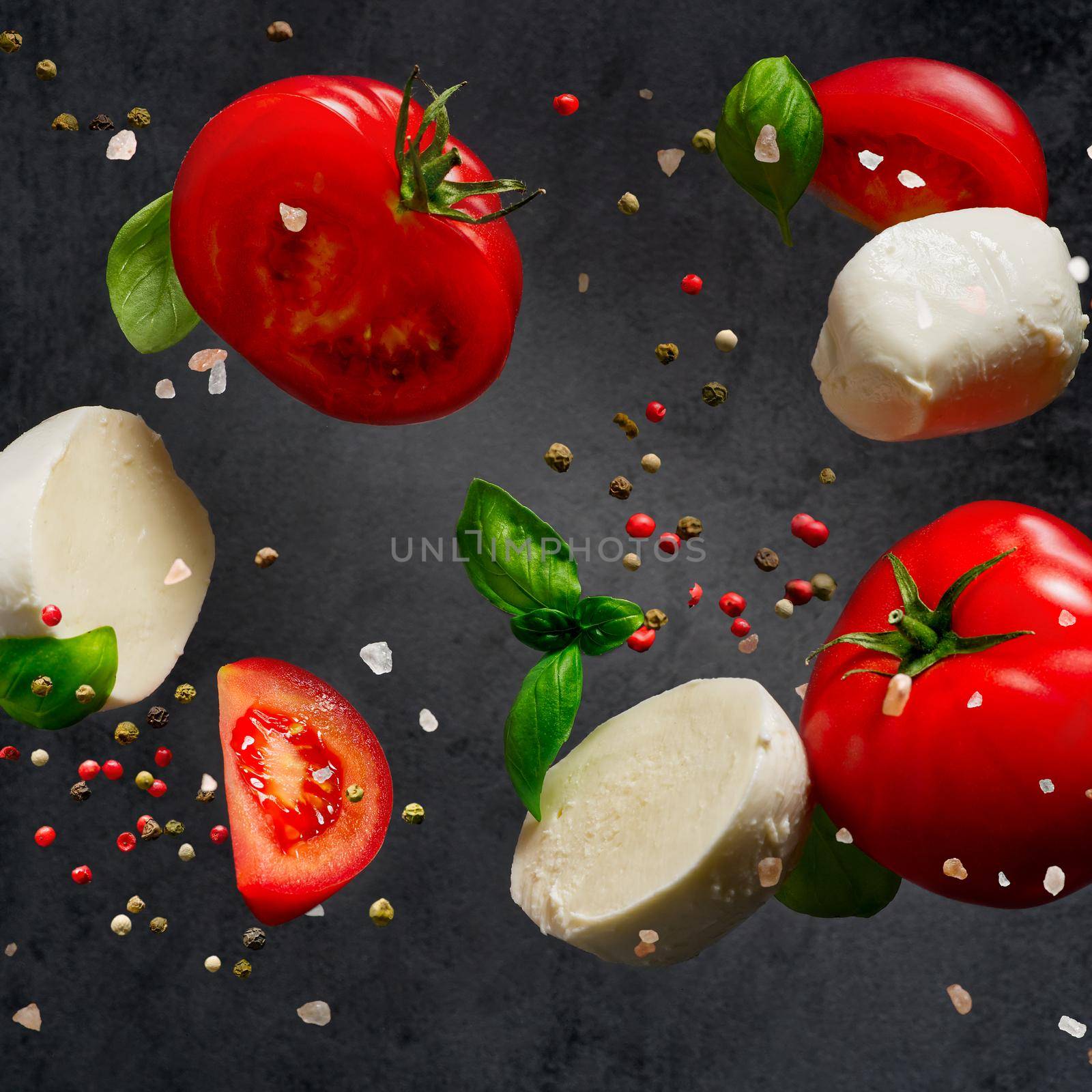 Falling caprese salad ingredients on dark background. Italian appetizer by PhotoTime
