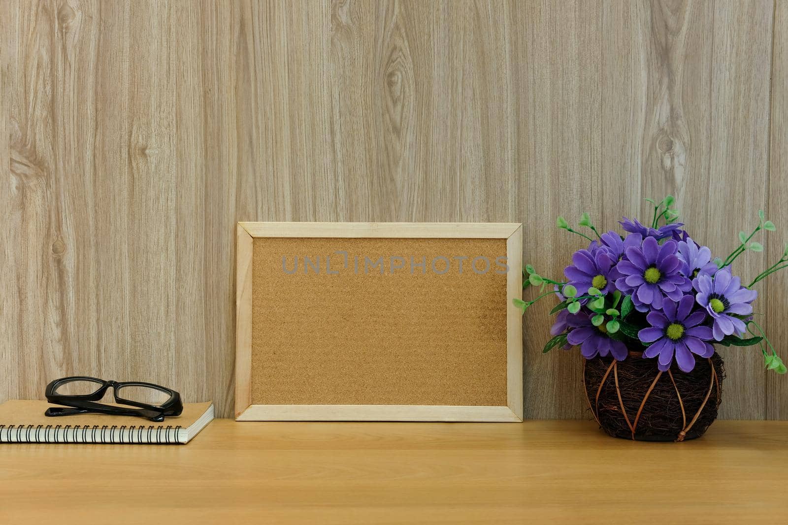 cork board notebook glasses artificial flower on wooden table at office workplace