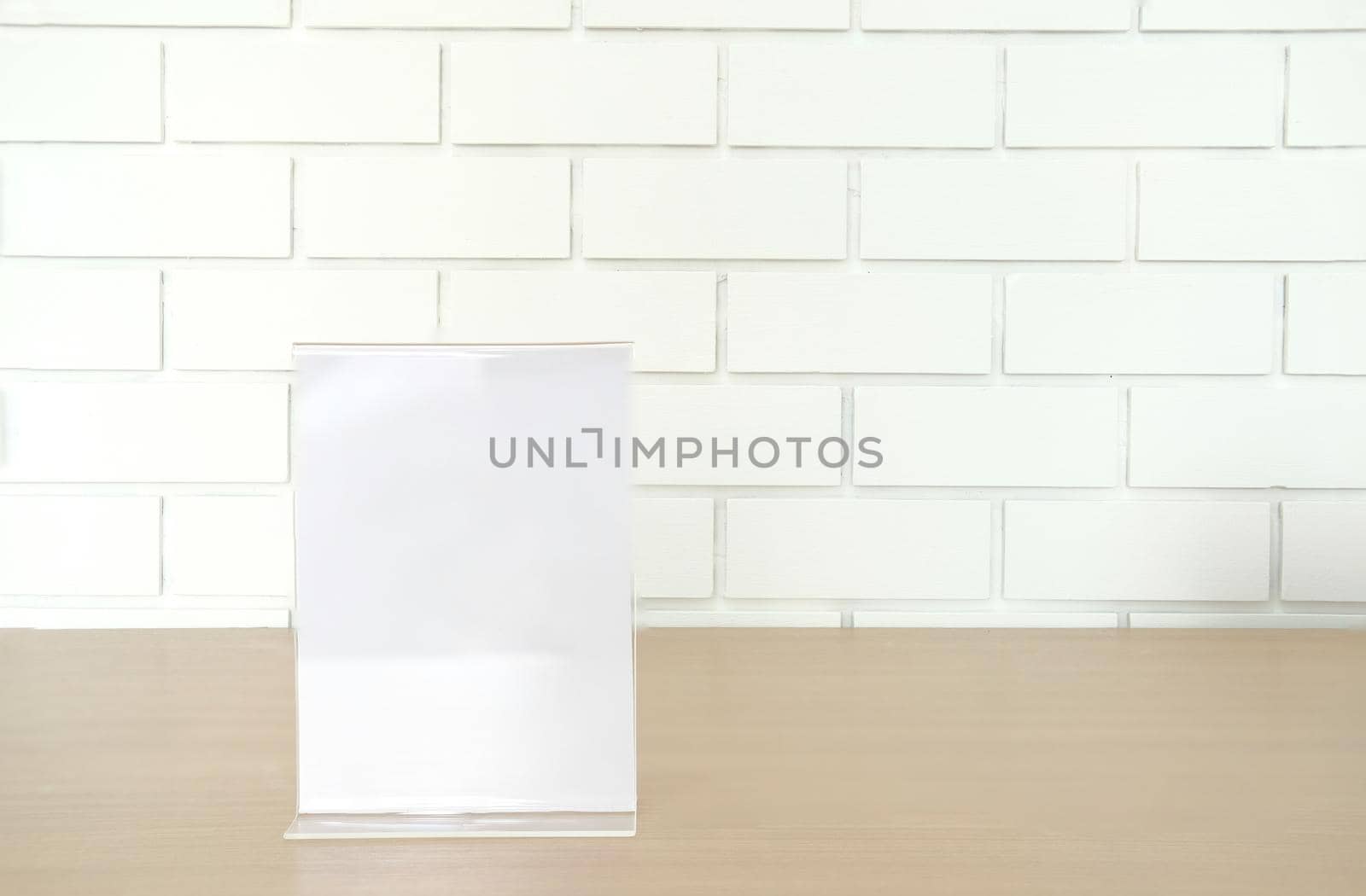 white label in cafe. display stand for acrylic tent card near white brick wall. mockup menu frame on table in restaurant. space for text