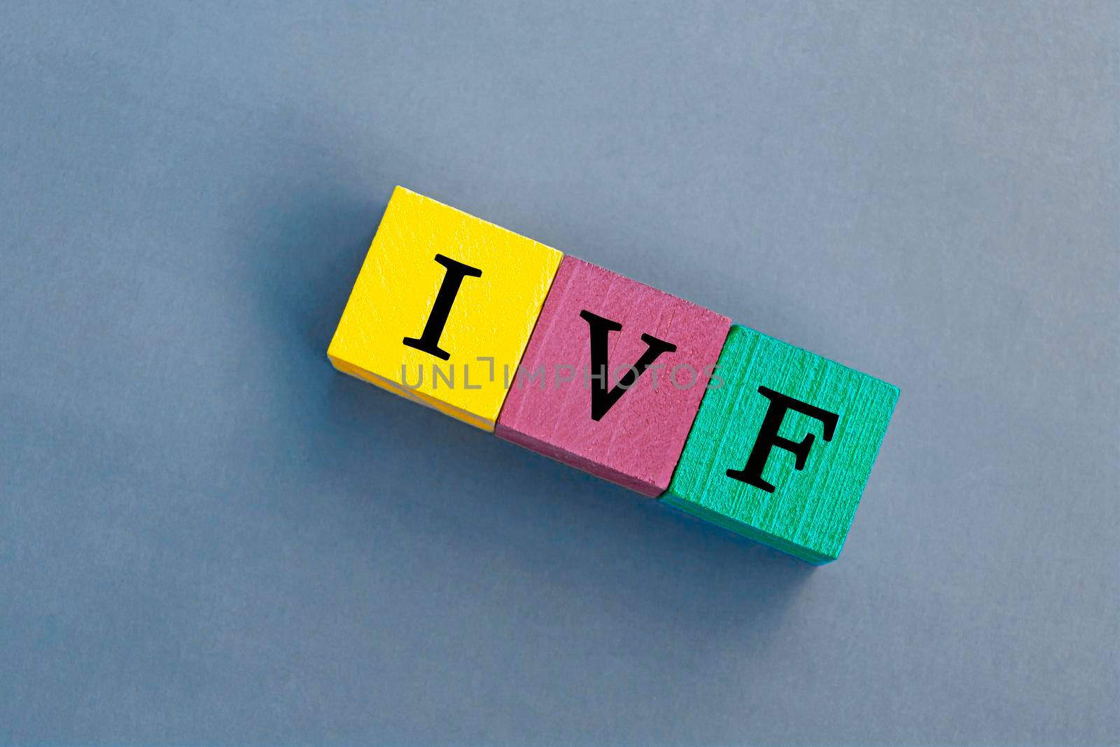 IVF acronym on colorful wooden cubes against blue background. In Vitro Fertilization. Flat lay. Copy Space. Directly above.