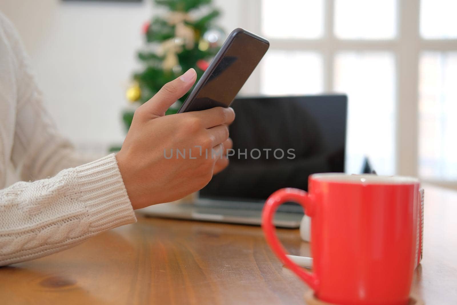 man using smartphone at home. woman texting message on mobile phone during xmas. christmas new year holiday celebration season greetings