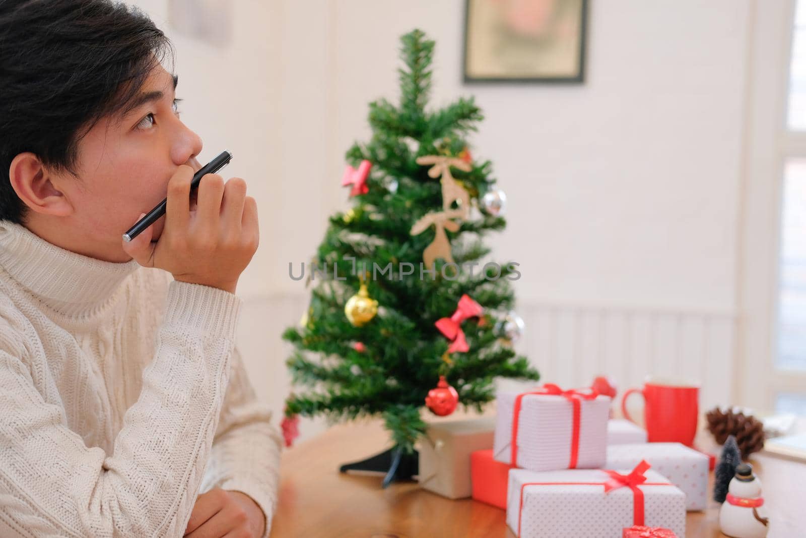 man wearing cream sweater thinking with pensive expression. christmas decoration at xmas new year holiday celebration.