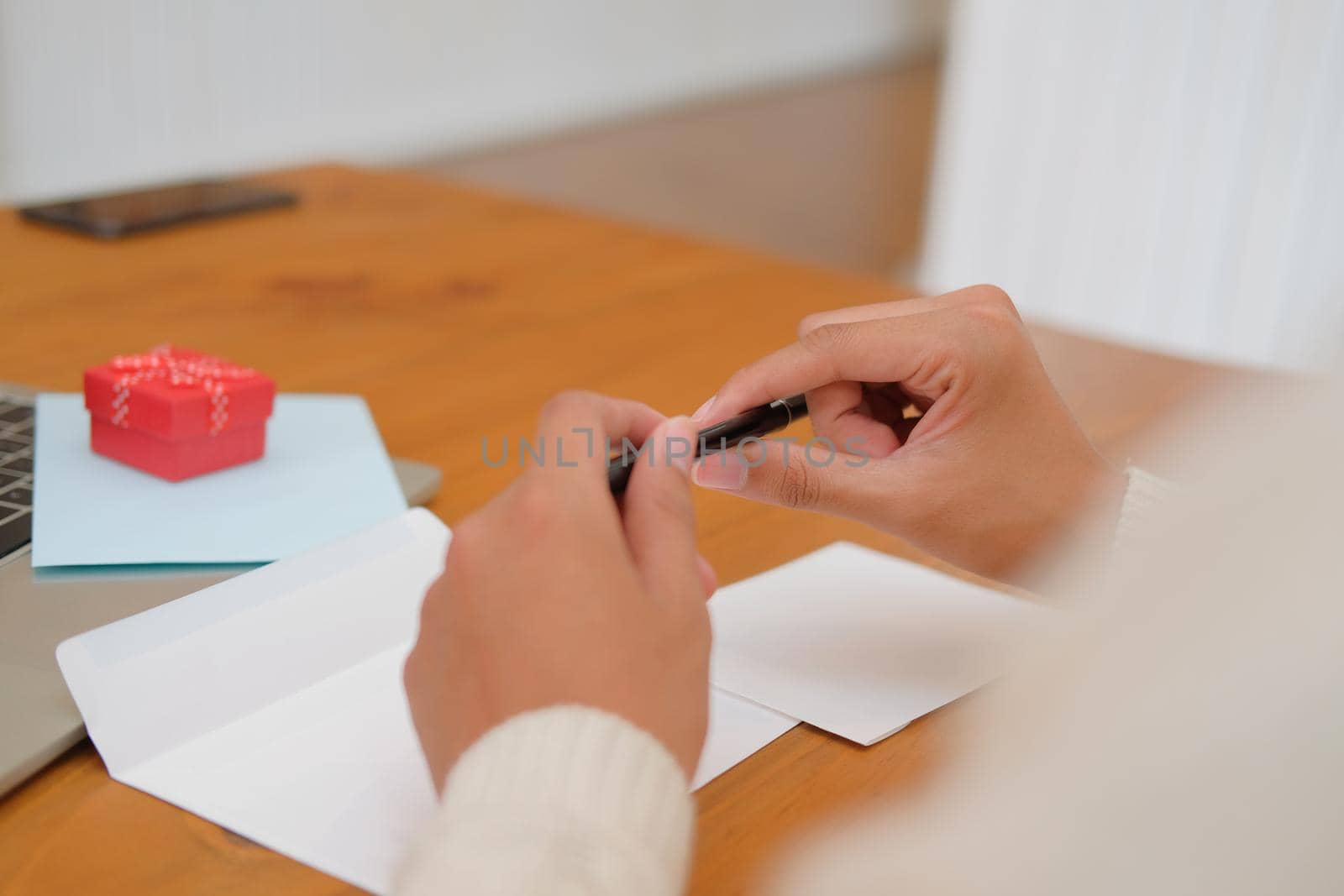 man wearing cream sweater thinking writing christmas letter greeting card holiday wishes with xmas decoration.