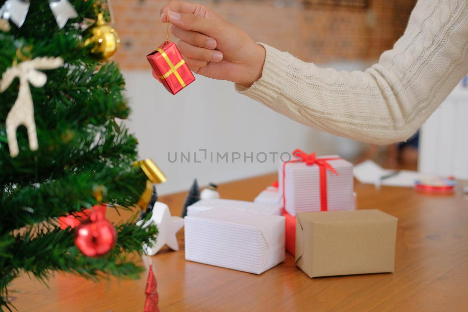 man wearing cream sweater decorating christmas tree. xmas new year holiday celebration.