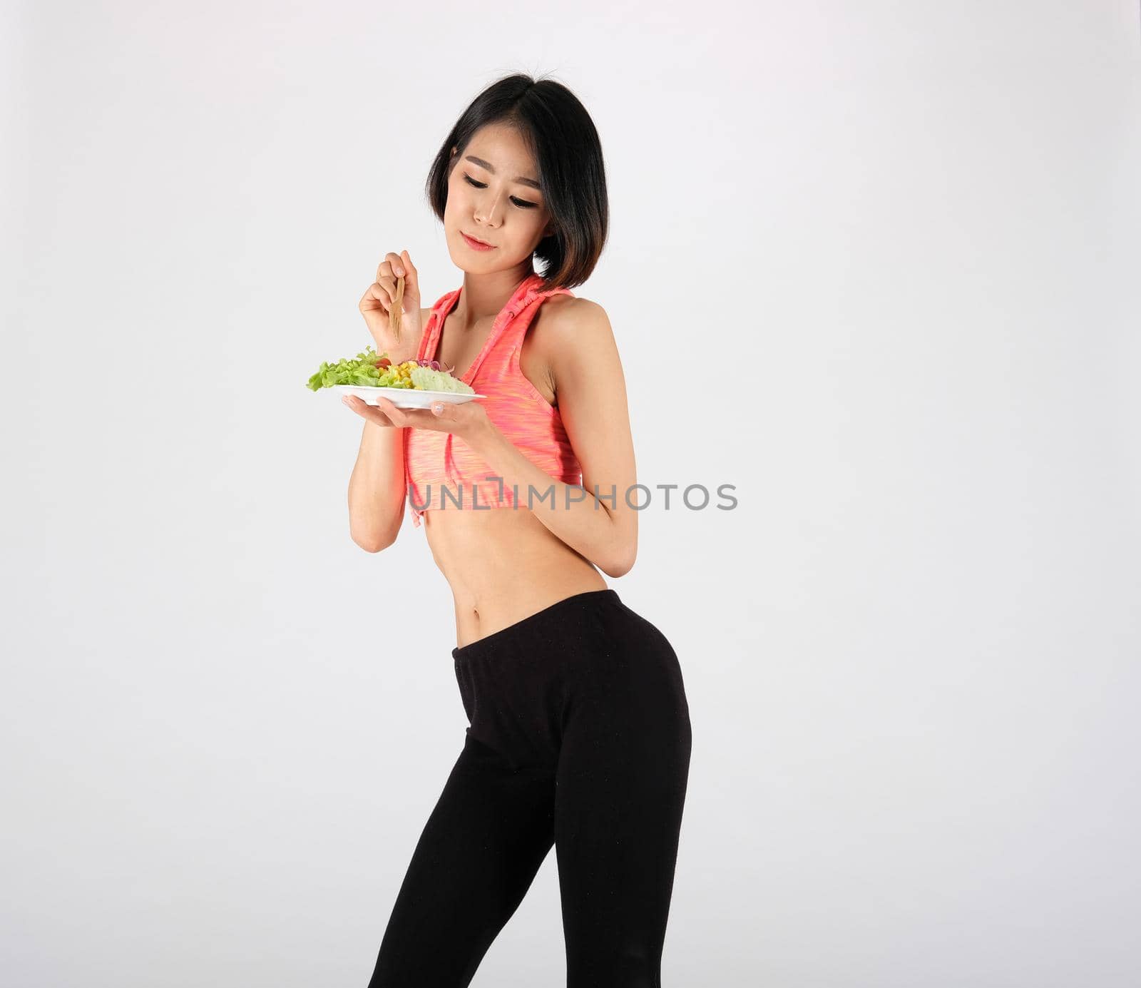 sporty fitness woman in sportswear with vegetable salad bowl on white background. healthy sport lifestyle
