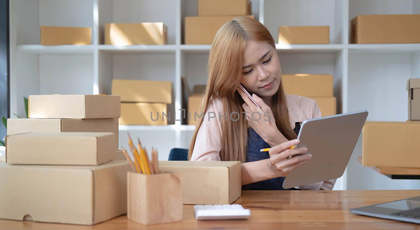 Small start-up business owners using computers and phones at work, salespeople, checking production orders. Pack products to ship to customers, sell ecommerce shipping ideas..