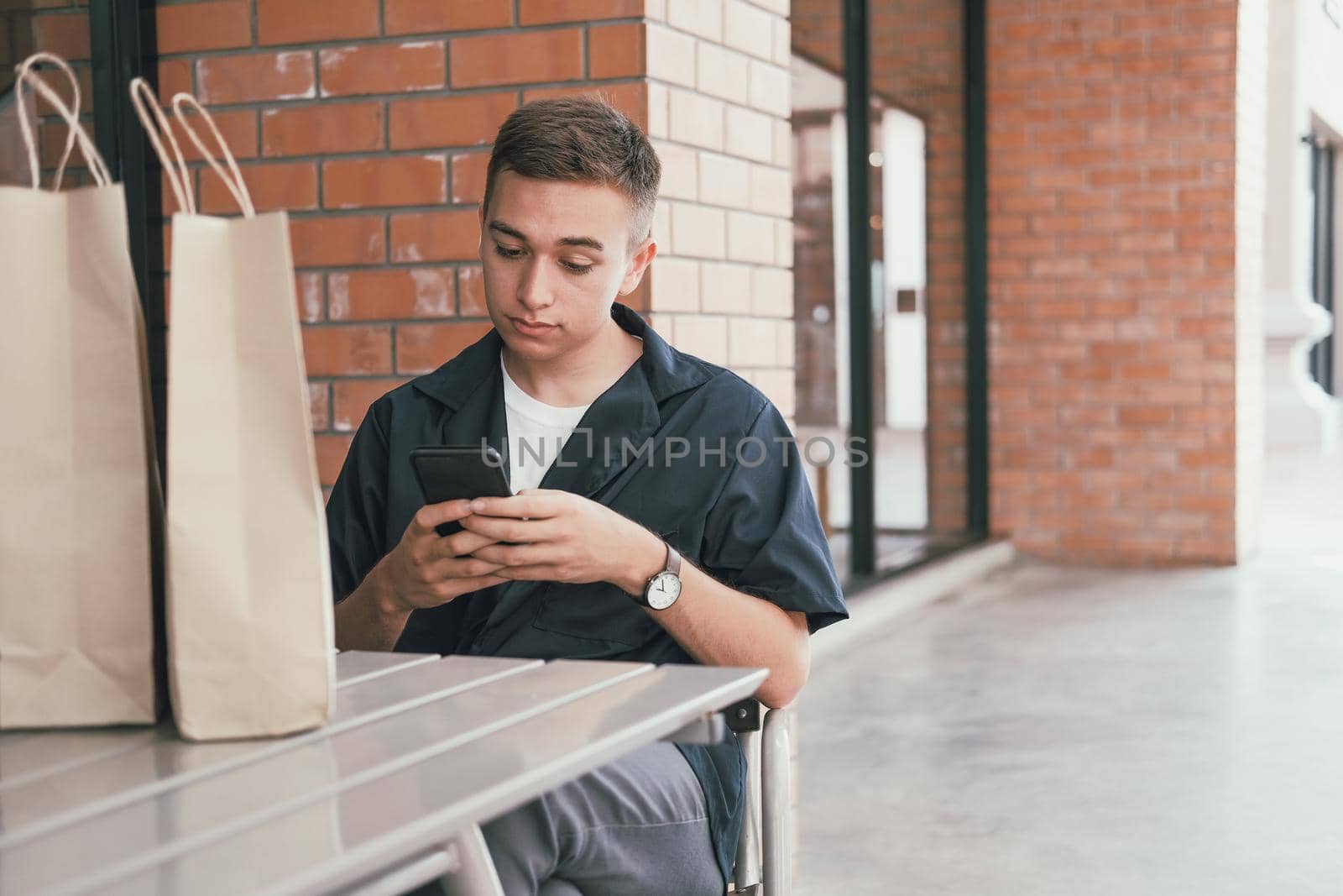 man using mobile smart phone with paper shopping bags. consumerism lifestyle