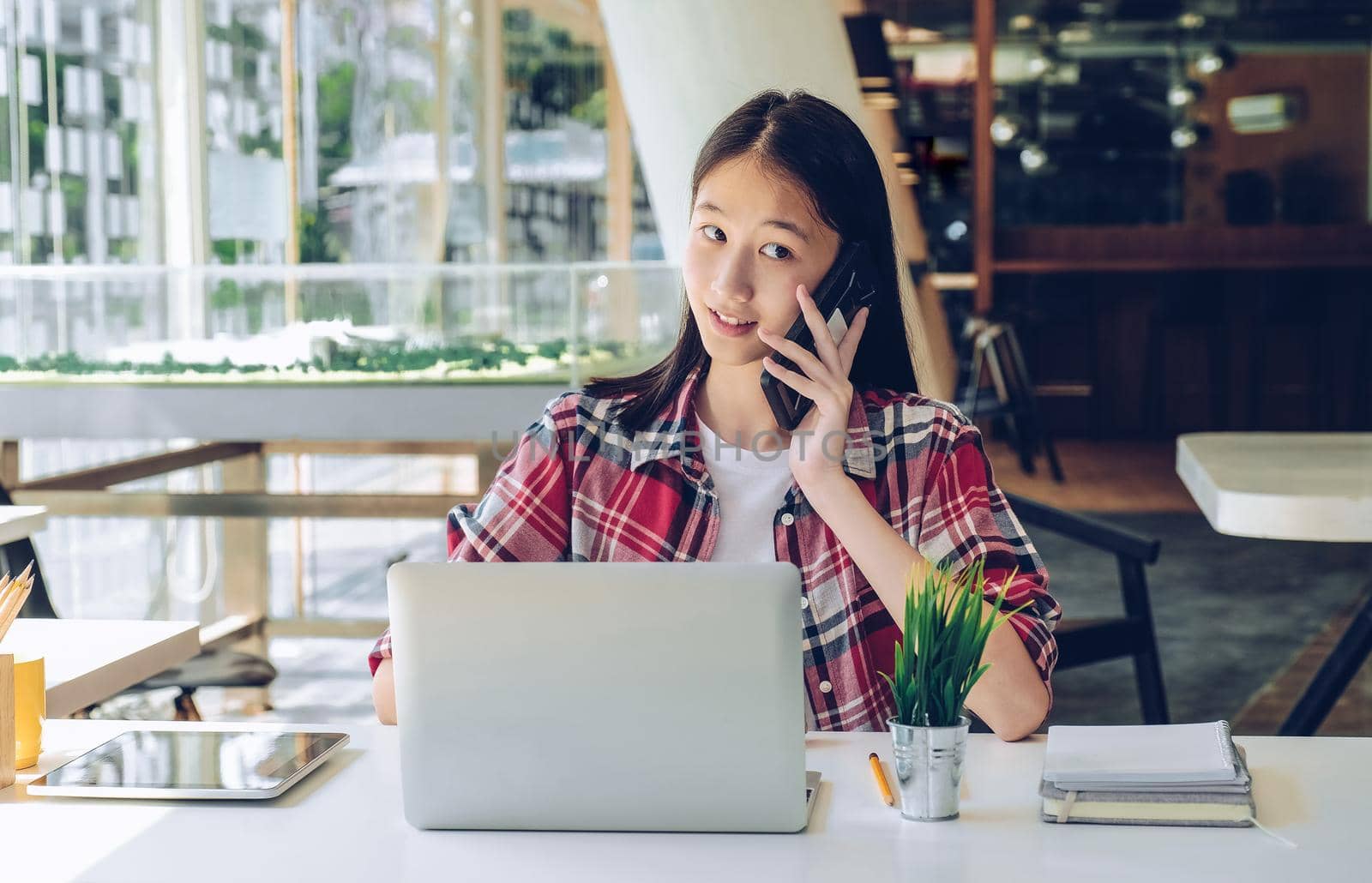 woman girl teenager freelancer talking on phone working on computer at workplace