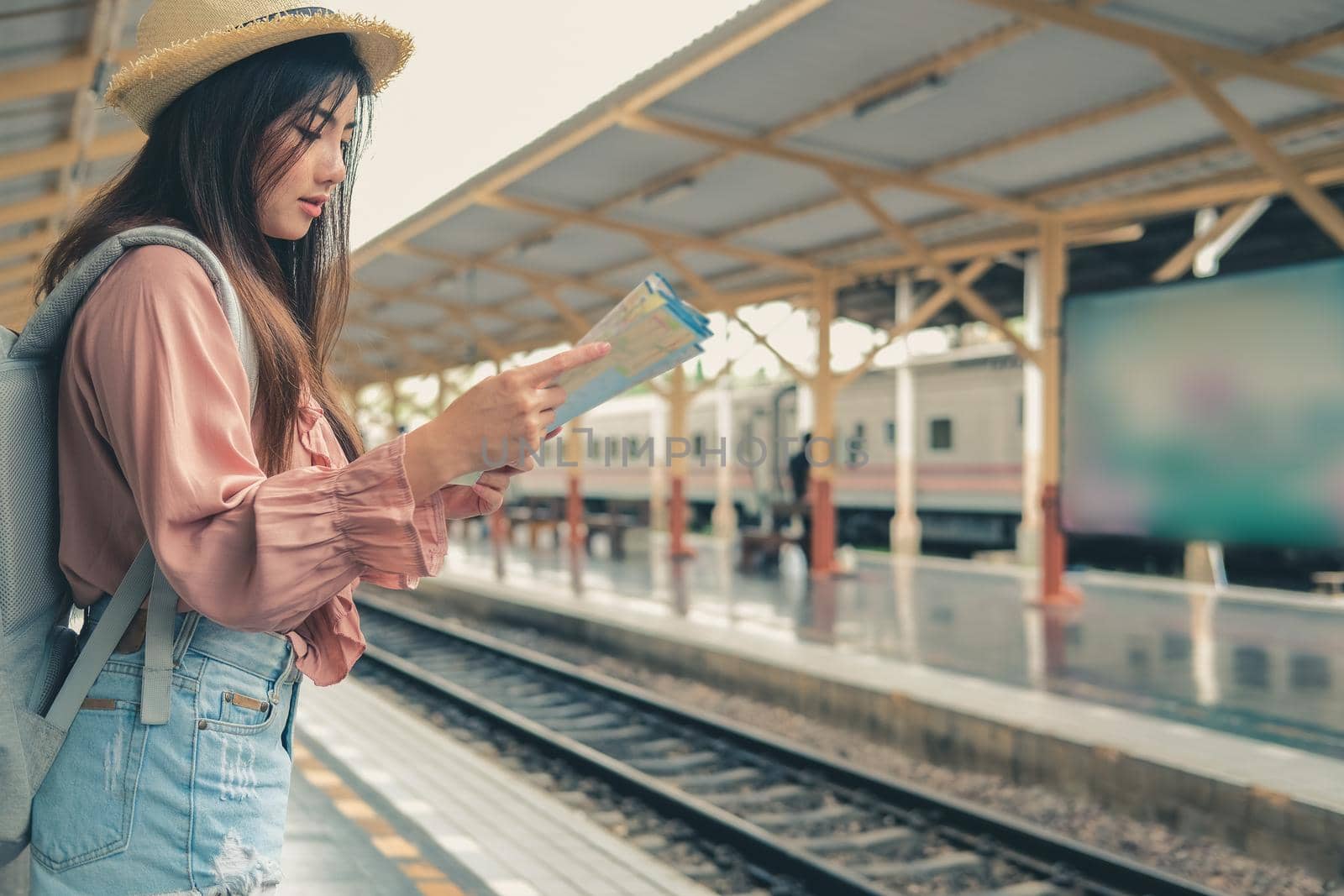 woman backpacker traveler looking at map with backpack at train station while waiting for train. journey trip travel concept by pp99