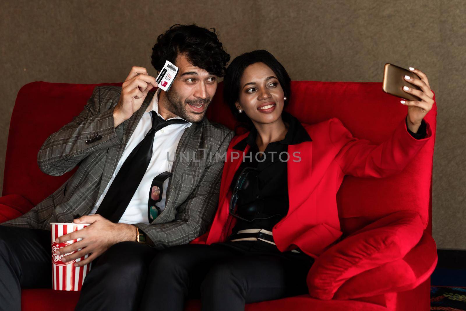 A couple man and woman take a photo with a ticket while sitting and waiting In front of the cinema